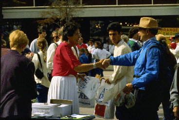 Two humans shake hands at an outdoor event.